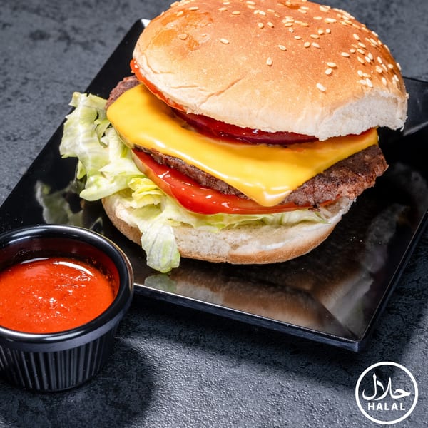 A Zaytoun Halal Grill cheeseburger with lettuce, tomato, and a side of red sauce.