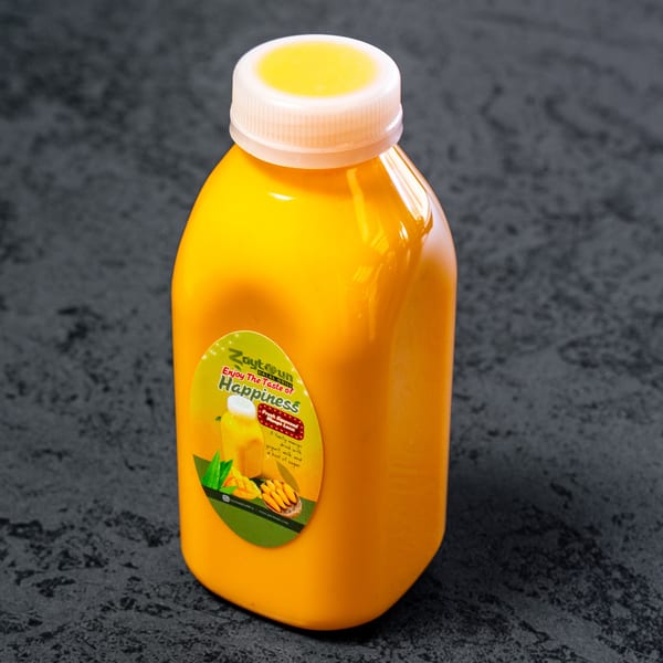 A Zaytun Halal Grill mango lassi bottle with a white cap on a dark gray surface.