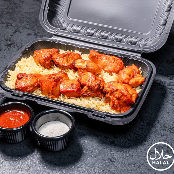 Halal chicken tikka with rice in a black takeout container, with red and white sauces.